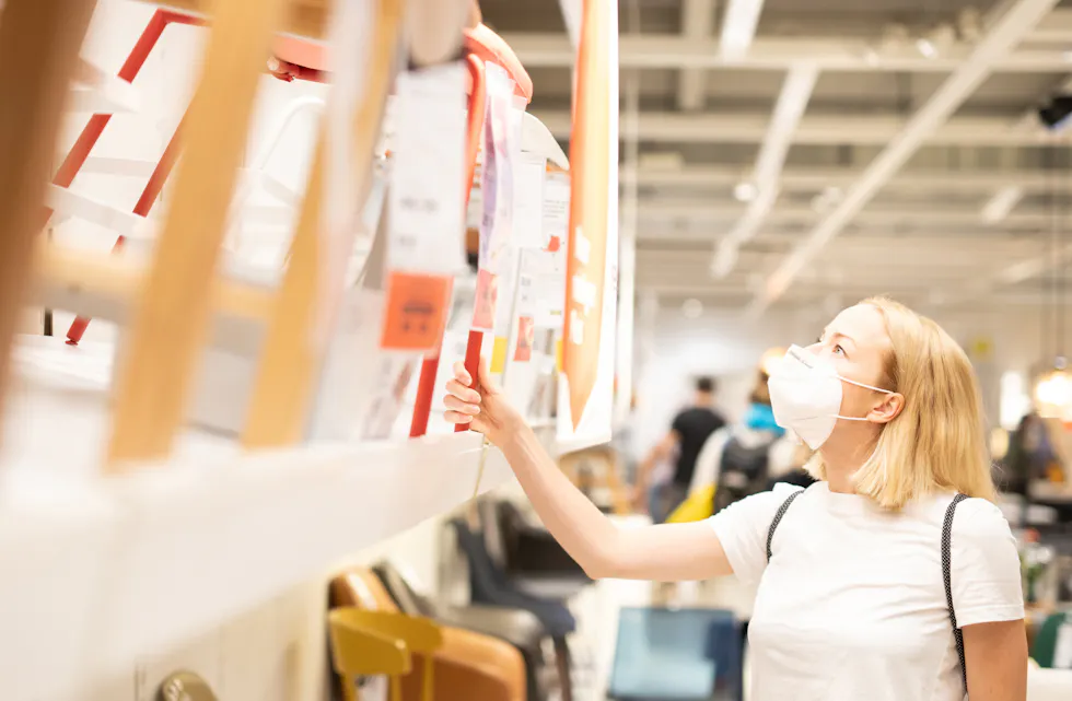 New normal during covid epidemic. Caucasian woman shopping at retail furniture and home accessories store wearing protective medical face mask to prevent spreading of corona virus