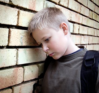 upset boy leaning against a wall