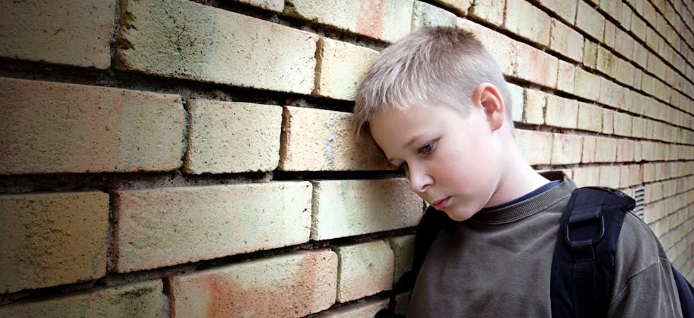 upset boy leaning against a wall
